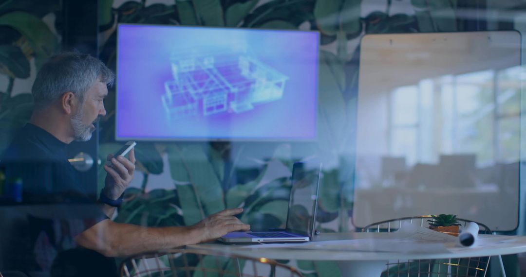 Architect holding phone and working on laptop in glass meeting room with blueprint display