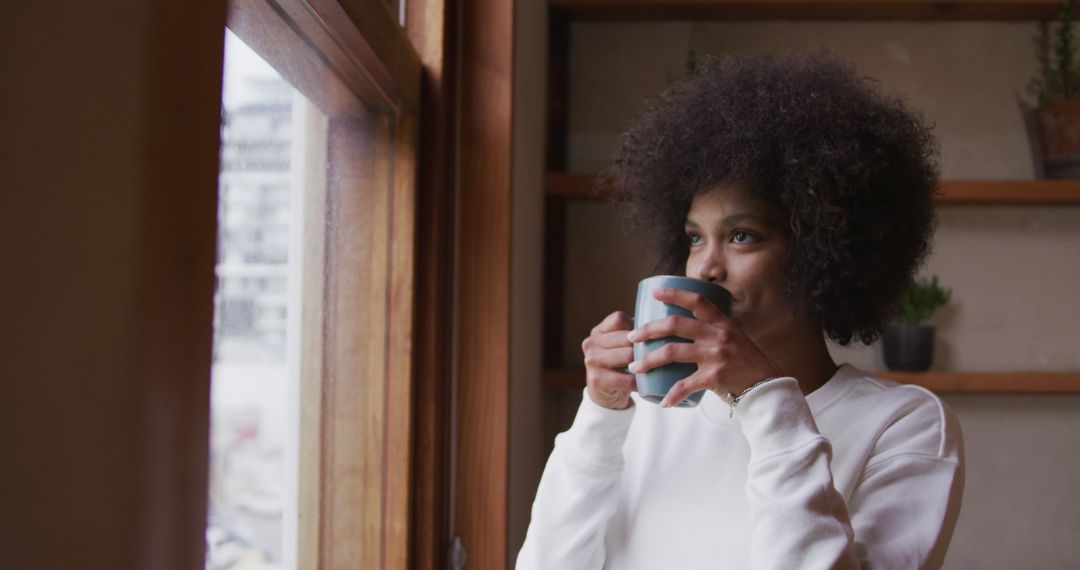 Woman Enjoying Coffee by Window with Thoughtful Expression - Free Images, Stock Photos and Pictures on Pikwizard.com