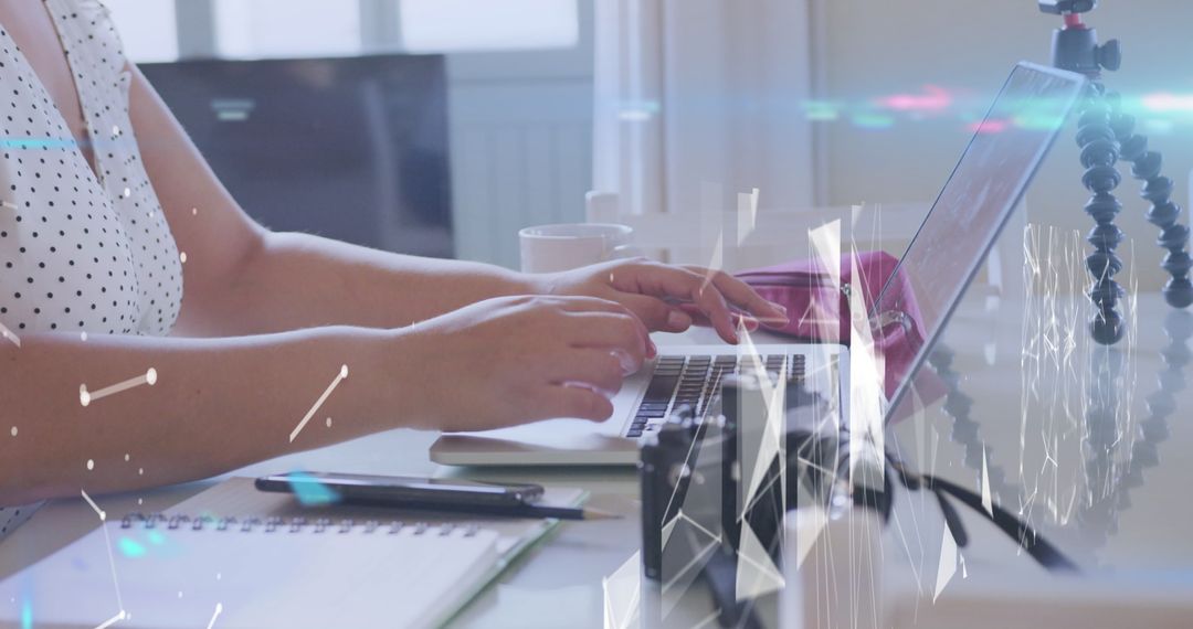 Woman Typing on Laptop at Modern Workspace with Camera and Notes