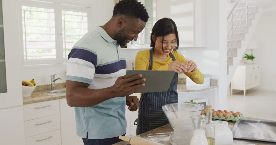 Happy diverse couple using tablet and baking in kitchen - Free Images, Stock Photos and Pictures on Pikwizard.com