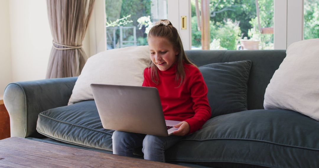 Happy Girl Using Laptop on Couch at Home