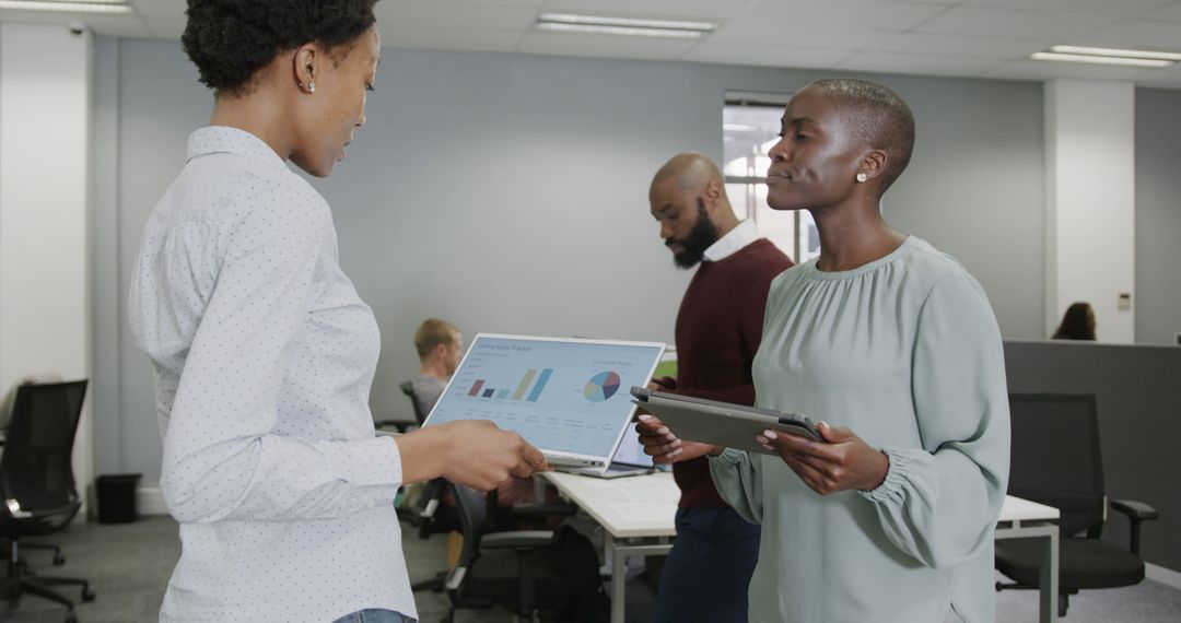 Colleagues Discussing Data with Tablets in Modern Office
