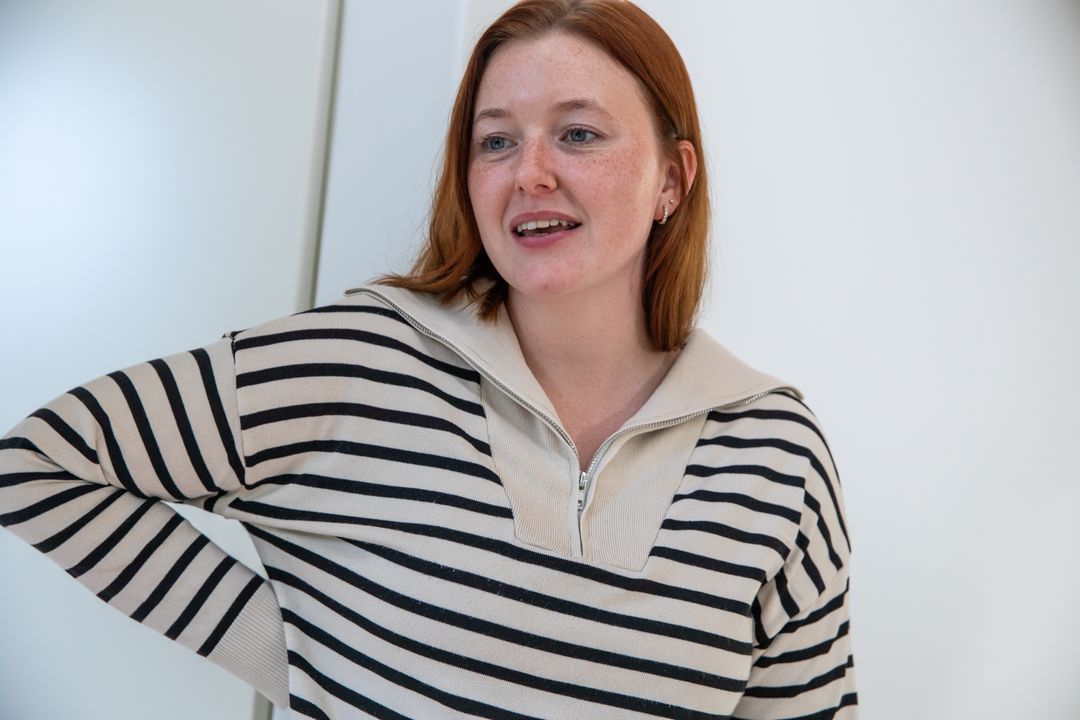 Woman in Striped Sweater Smiling in Minimalist Studio Setting