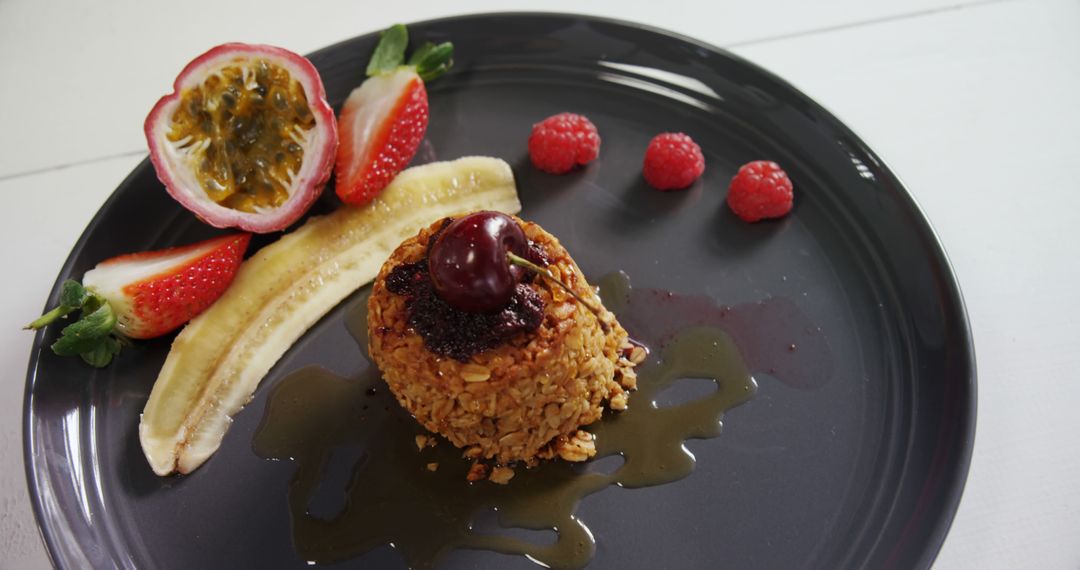 Gourmet Dessert with Berries and Nut-Coated Ice Cream on Black Plate