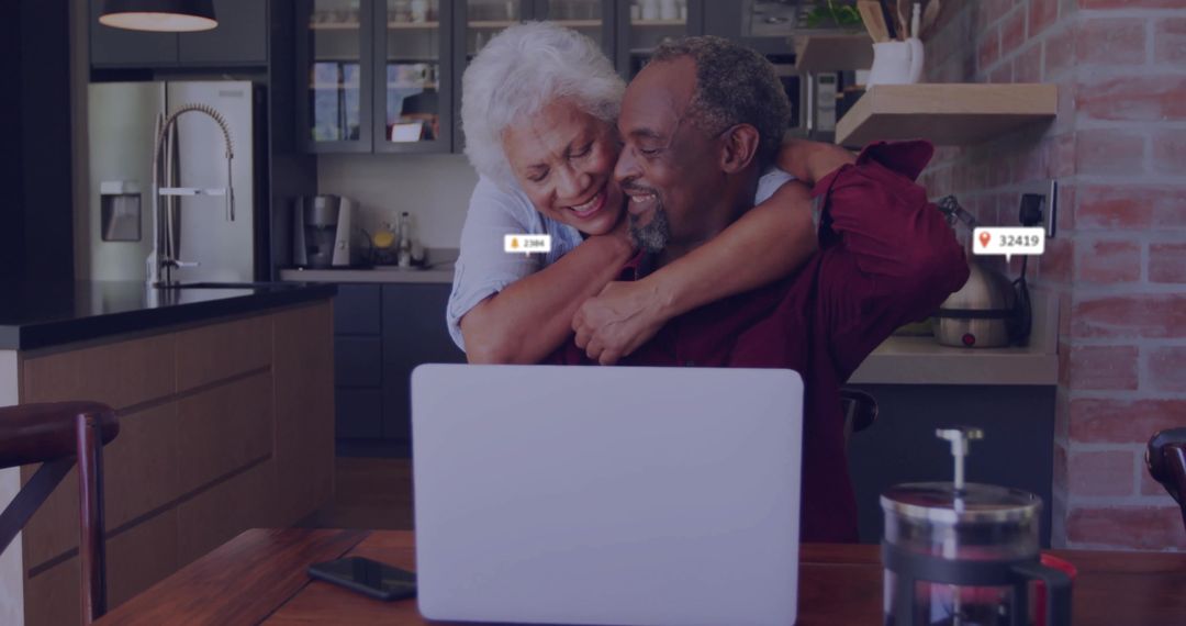 Senior Couple Embracing While Using Laptop in Modern Kitchen
