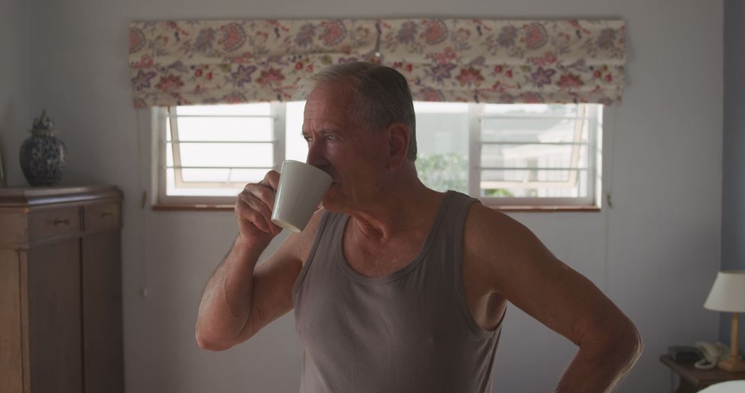 Elderly man drinking coffee in sunny living room - Free Images, Stock Photos and Pictures on Pikwizard.com