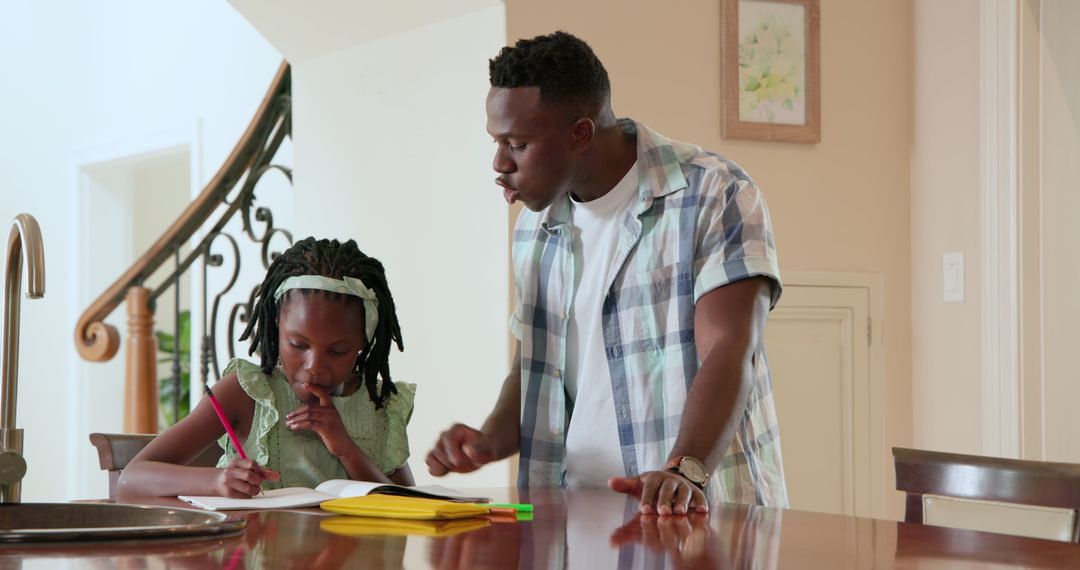 Father Assisting Daughter with Homework in Home Environment