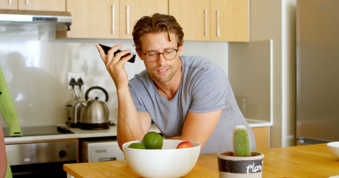 Young Man Talking on Phone in Modern Kitchen - Free Images, Stock Photos and Pictures on Pikwizard.com