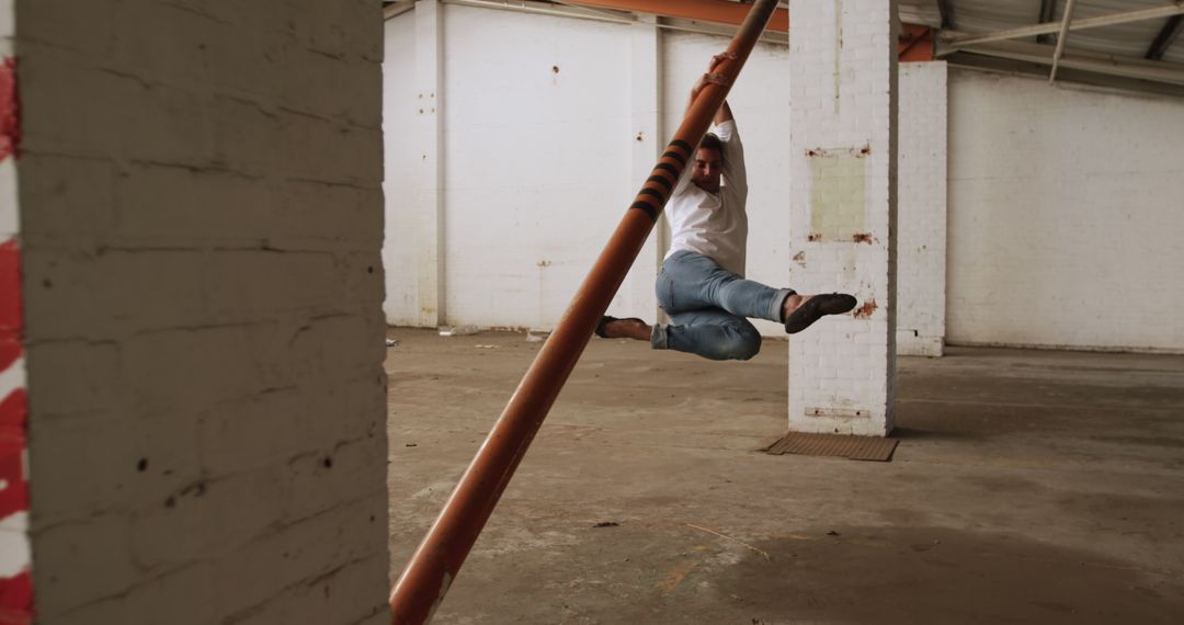 Man Swinging from Pole in Abandoned Warehouse - Free Images, Stock Photos and Pictures on Pikwizard.com