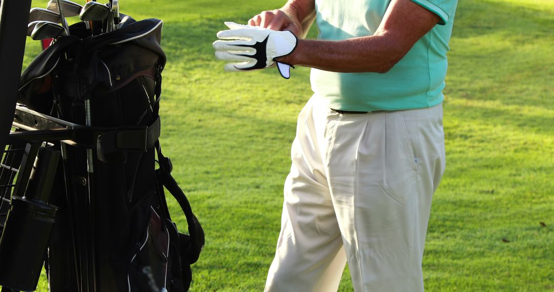 Man Preparing for Golf Game Wearing White Golf Glove on Course
