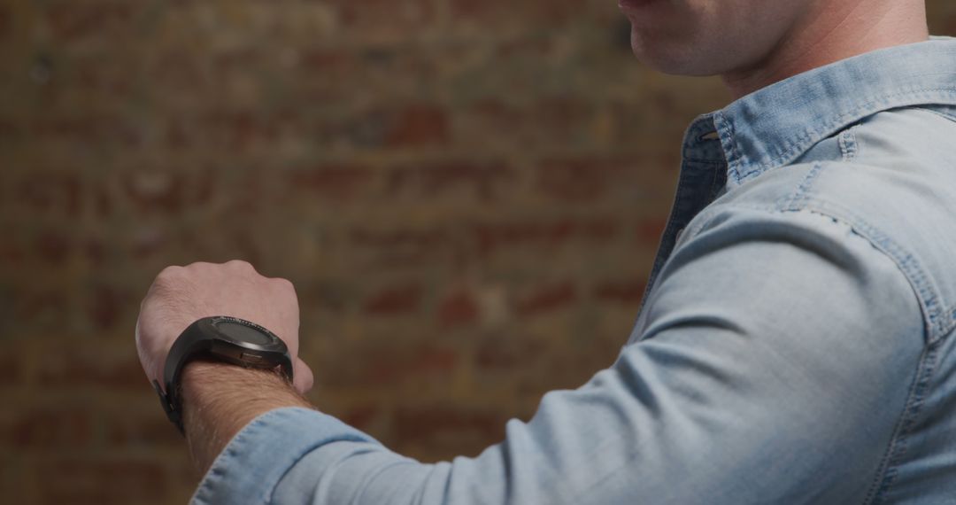 Man in Denim Shirt Checking Time on Smartwatch Indoors - Free Images, Stock Photos and Pictures on Pikwizard.com