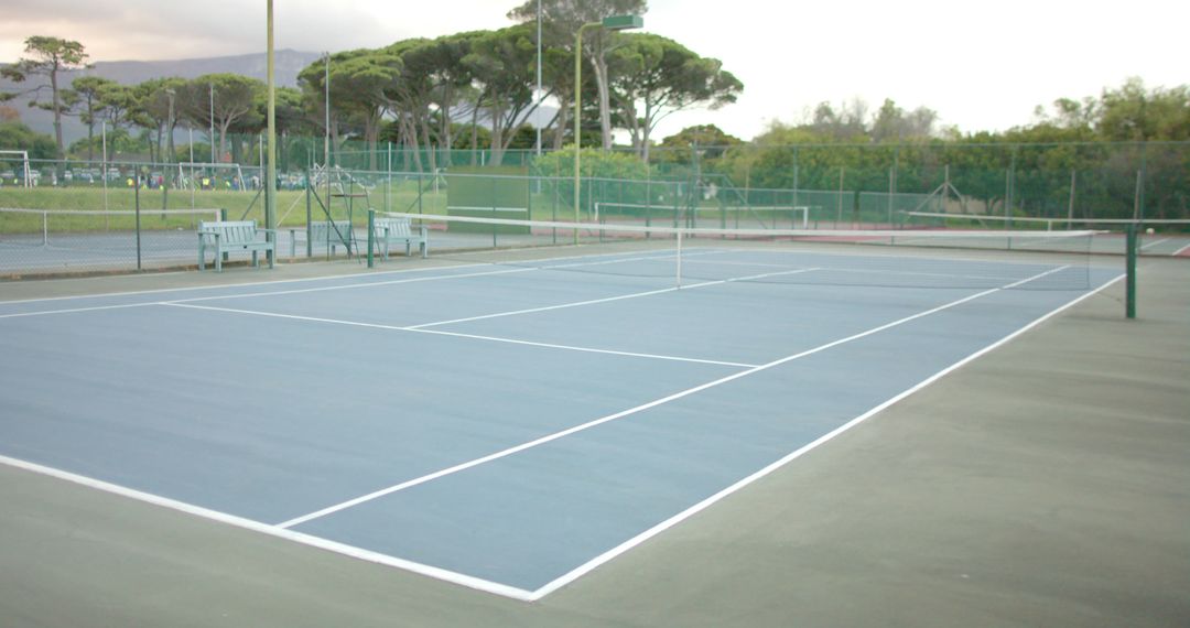 Empty Outdoor Tennis Court with Net Surrounded by Greenery - Free Images, Stock Photos and Pictures on Pikwizard.com