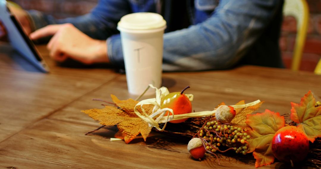 Person Using Tablet with Coffee Cup on Wooden Table with Autumn Decorations - Free Images, Stock Photos and Pictures on Pikwizard.com