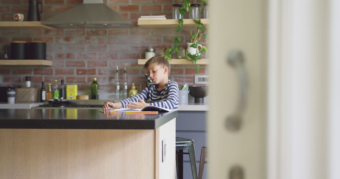 Young Boy Studying in Modern Kitchen with Brick Wall Background - Free Images, Stock Photos and Pictures on Pikwizard.com