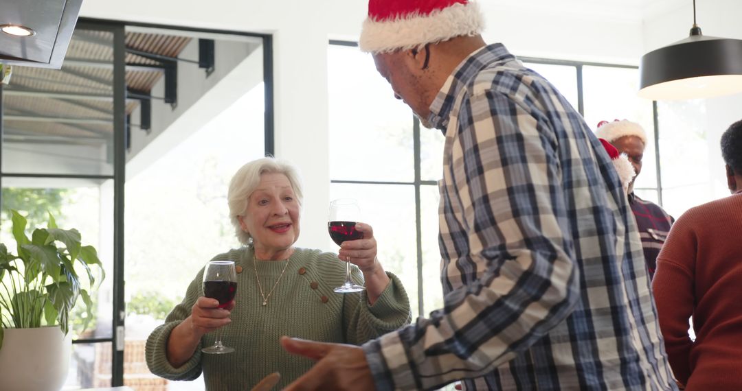 Senior Couple Celebrating Christmas with Wine Laughing Together Indoors - Free Images, Stock Photos and Pictures on Pikwizard.com