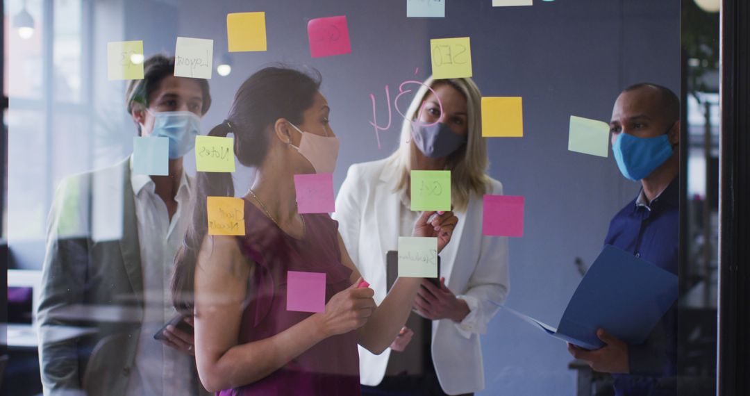 Diverse Team in Masks Collaborating with Post-it Notes