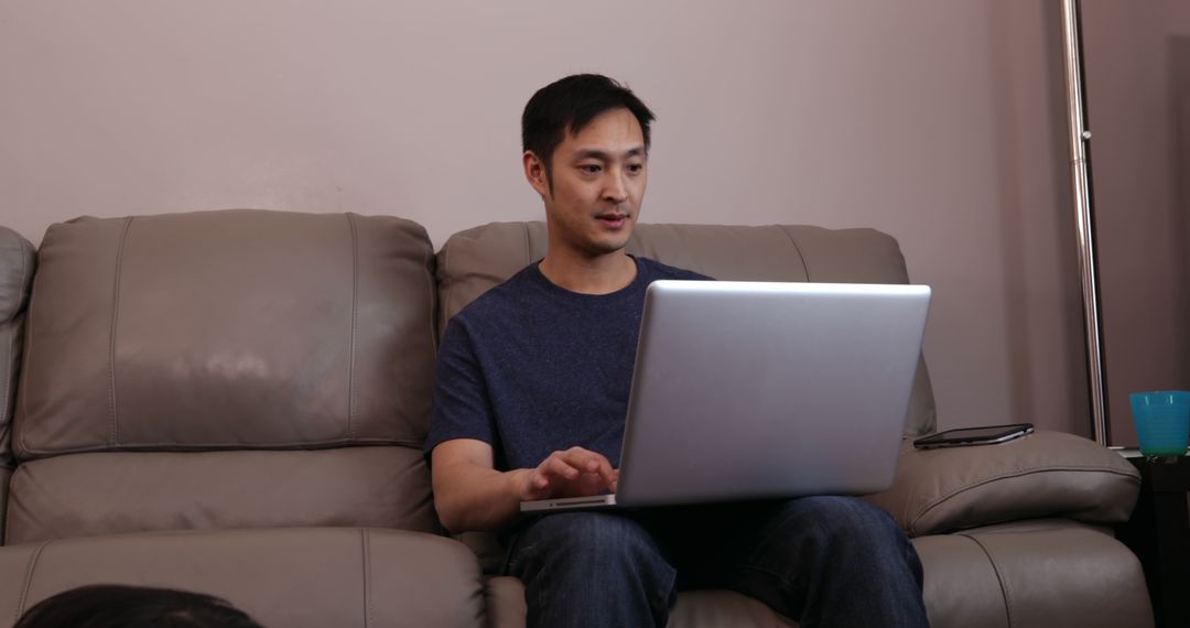 Man Using Laptop at Home on Couch - Free Images, Stock Photos and Pictures on Pikwizard.com