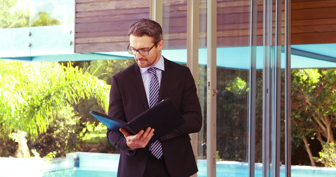 Businessman Reviewing Documents by Swimming Pool - Free Images, Stock Photos and Pictures on Pikwizard.com