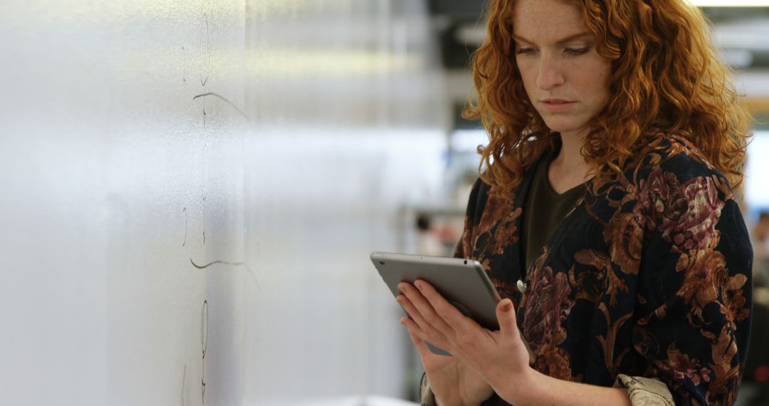 Focused Redheaded Woman Using Tablet in Office - Free Images, Stock Photos and Pictures on Pikwizard.com