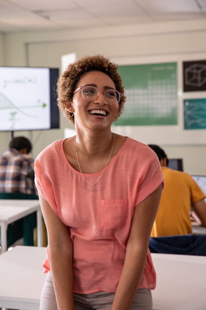 African American teacher smiling and guiding teens on computers in modern classroom