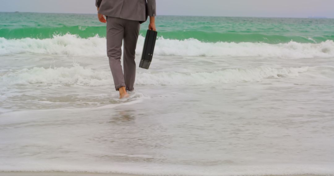 Businessman Relaxing Barefoot on Beach Shoreline with Briefcase