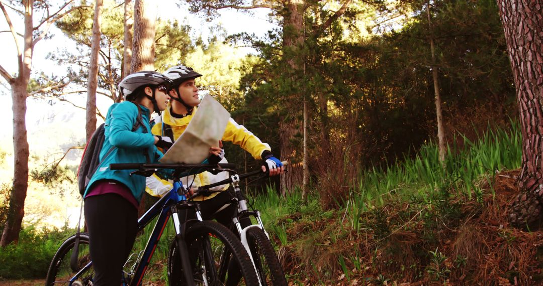 Young couple cycling and navigating with map in forest - Free Images, Stock Photos and Pictures on Pikwizard.com