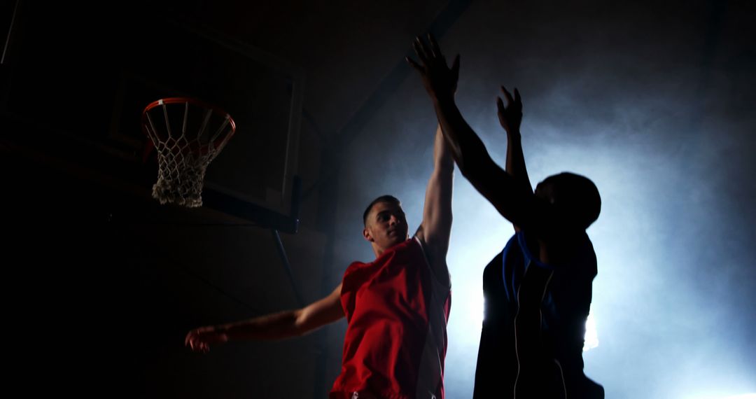 Rivals Competing in Intense Basketball Game Under Dramatic Lighting - Free Images, Stock Photos and Pictures on Pikwizard.com