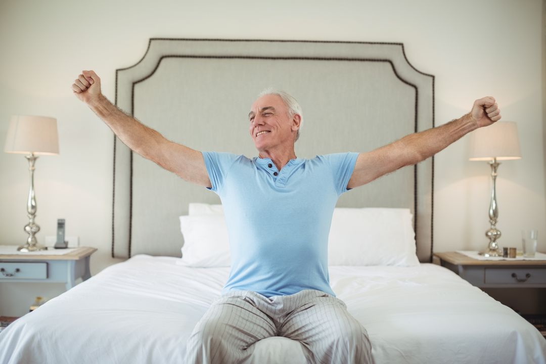 Senior man stretching arms on bed - Free Images, Stock Photos and Pictures on Pikwizard.com