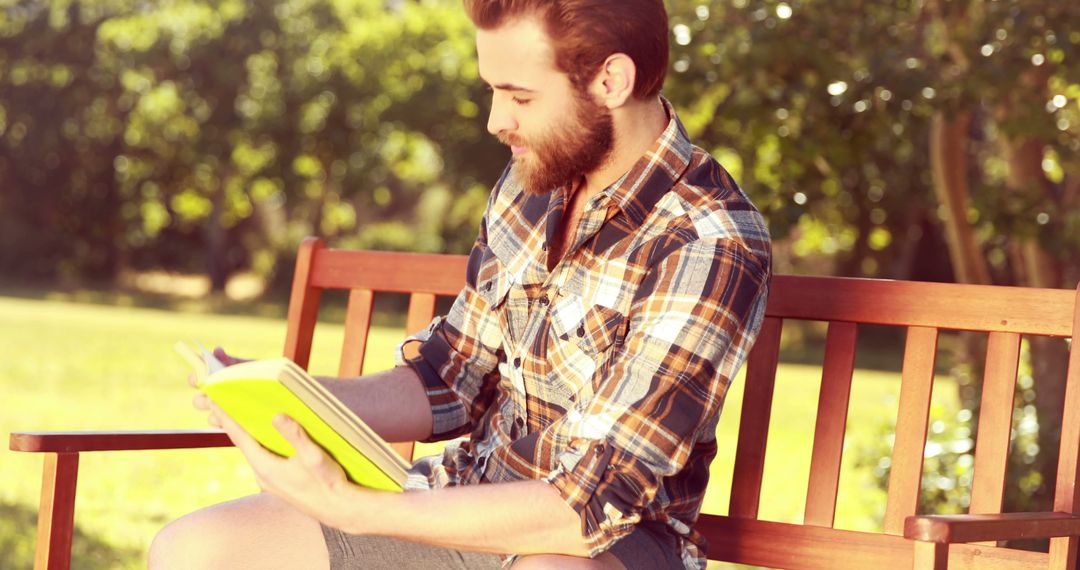 Young man enjoying reading book on park bench - Free Images, Stock Photos and Pictures on Pikwizard.com