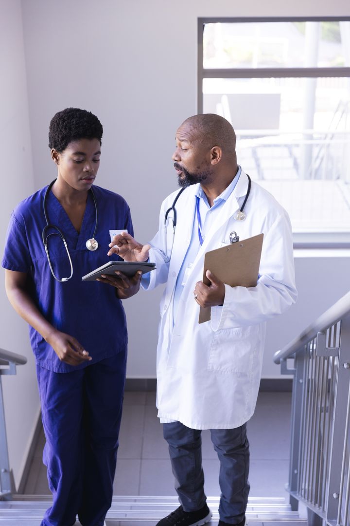 Doctors Discussing Patient Information on Staircase - Free Images, Stock Photos and Pictures on Pikwizard.com