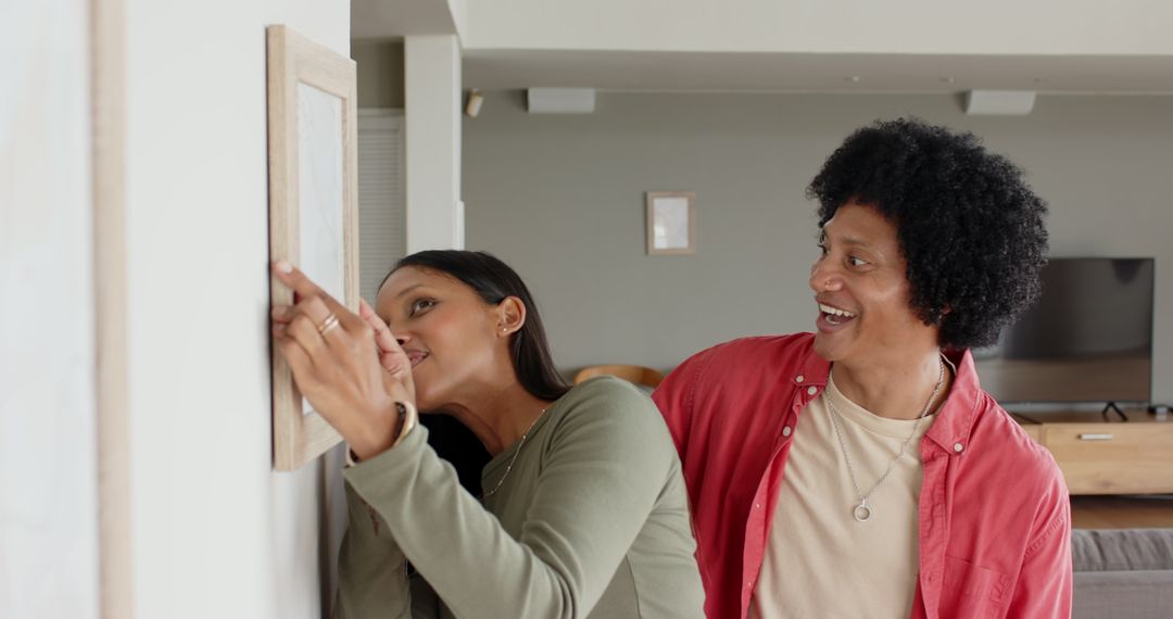 Diverse Couple Arranging Picture Frame in Cozy Living Room