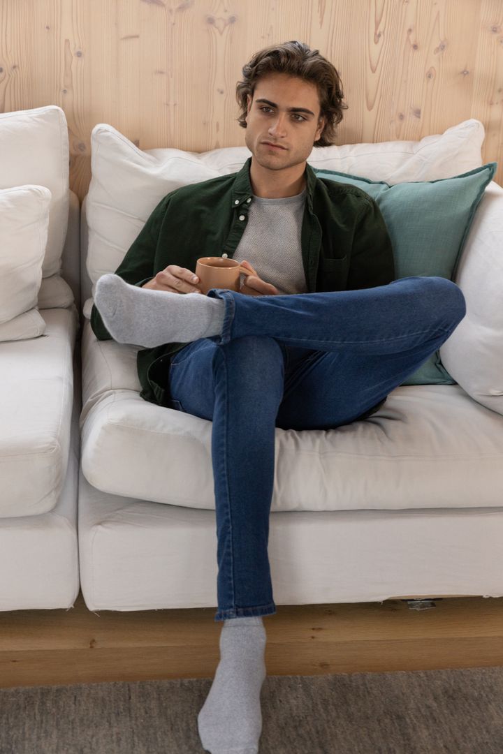 Young Man Relaxing on Sofa with Coffee Mug at Home