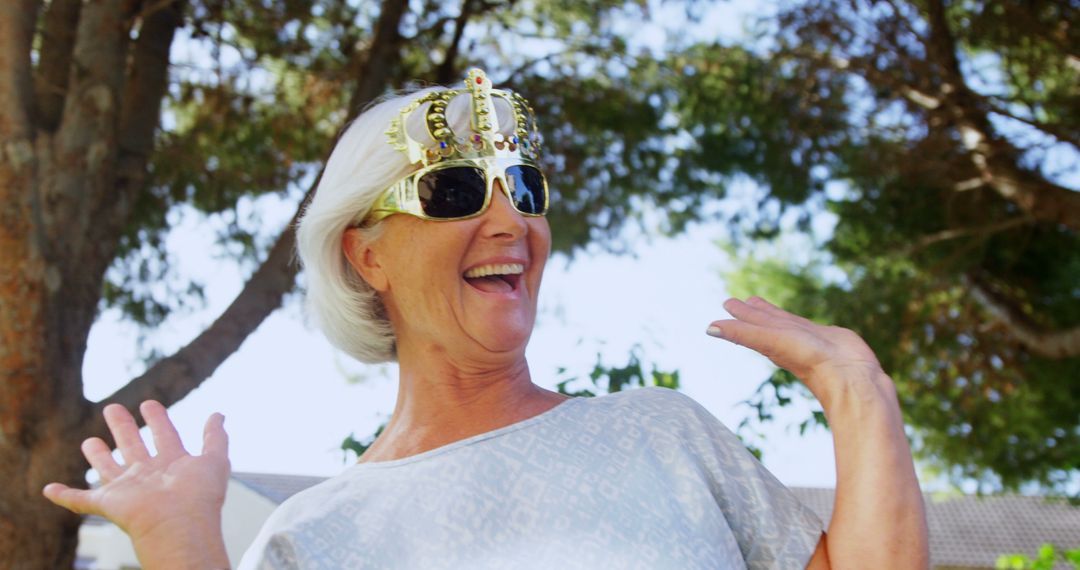 Cheerful Elderly Woman Wearing Fun Crown and Sunglasses Outdoors - Free Images, Stock Photos and Pictures on Pikwizard.com