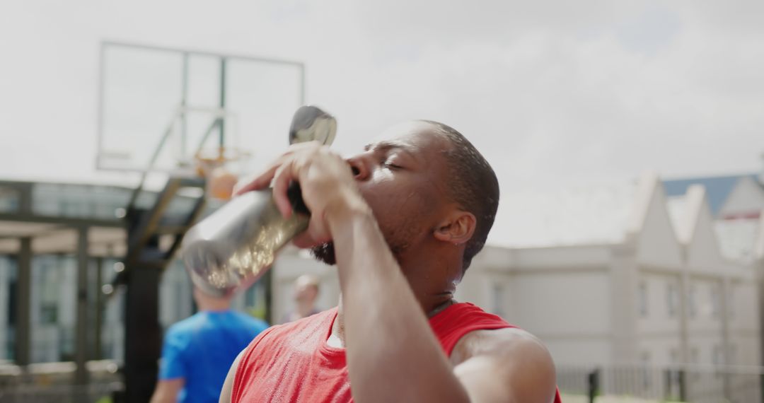 Athletic Man Drinking Water by Outdoor Basketball Court - Free Images, Stock Photos and Pictures on Pikwizard.com