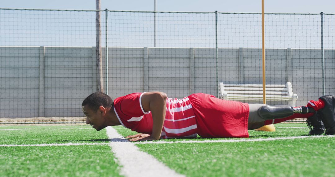 Determined male athlete with prosthetic leg doing push-up on soccer field - Free Images, Stock Photos and Pictures on Pikwizard.com