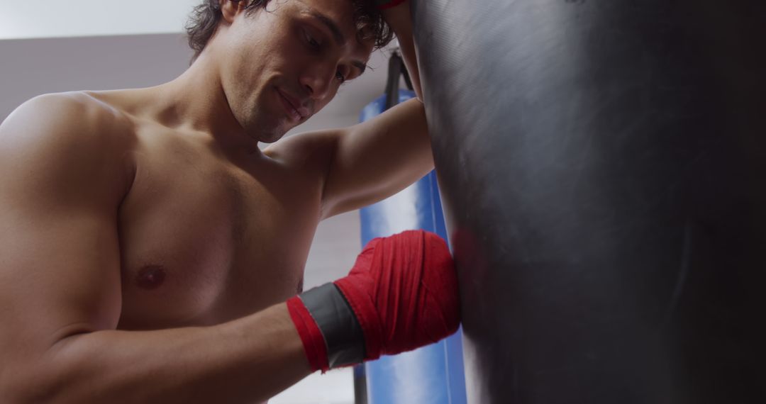 Male Boxer Wearing Red Hand Wraps at Punching Bag in Gym - Free Images, Stock Photos and Pictures on Pikwizard.com