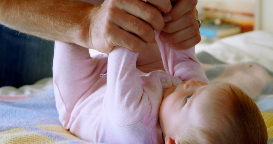 Father holding baby's hands in relaxing home atmosphere - Free Images, Stock Photos and Pictures on Pikwizard.com