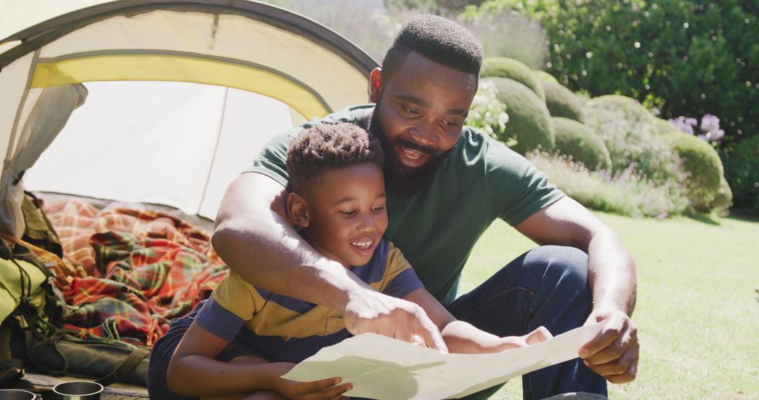 Joyful African American Father and Son Reading Together Outdoors - Free Images, Stock Photos and Pictures on Pikwizard.com