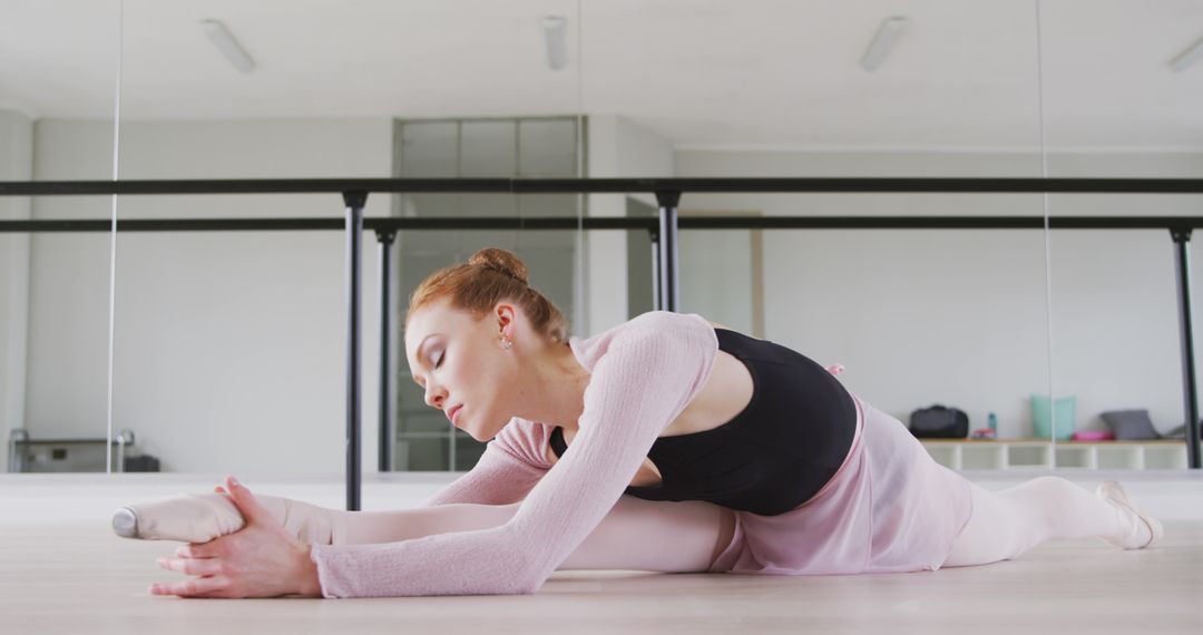 Dedicated Ballet Dancer Stretching in Dance Studio