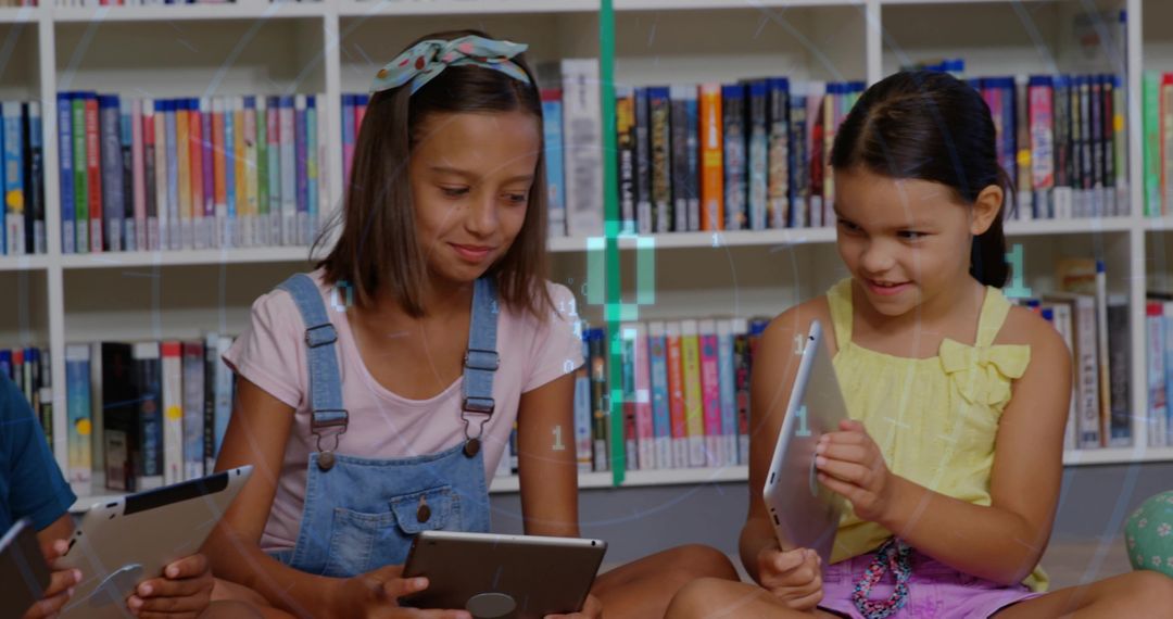 Two Girls Sitting in Library Using Tablets Sharing Digital Learning and Friendship