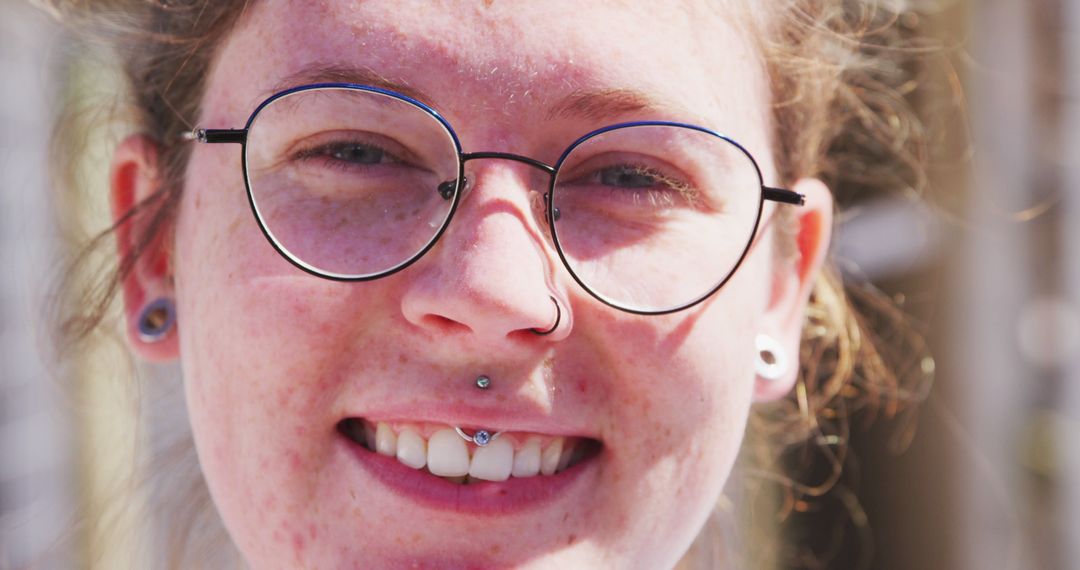 Young Woman with Glasses Smiling Under Sunlight - Free Images, Stock Photos and Pictures on Pikwizard.com