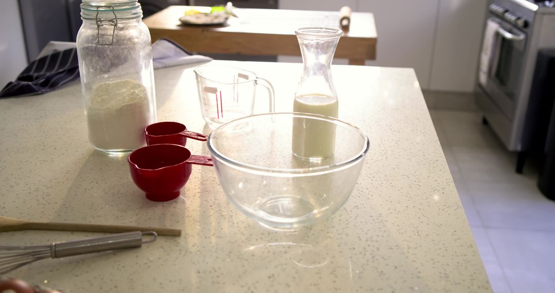 Baking Prep on Bright Kitchen Countertop with Glass Mixing Bowl and Red Measuring Cups