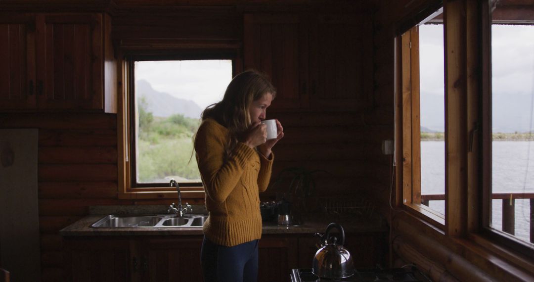 Woman Enjoying Hot Beverage by Window Inside Cozy Cabin - Free Images, Stock Photos and Pictures on Pikwizard.com