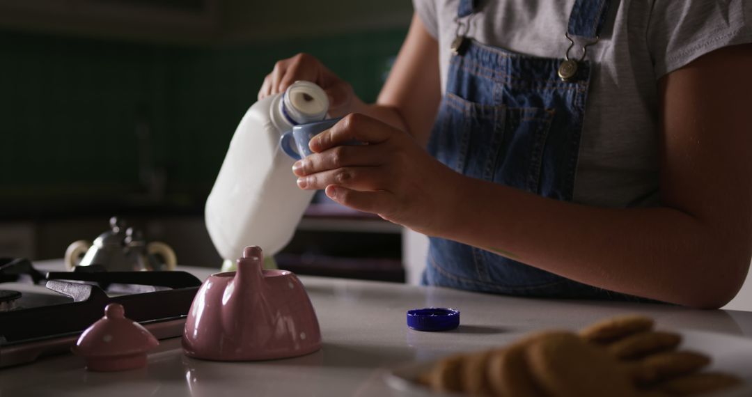 Child Pouring Milk Into Teapot in Kitchen Setting - Free Images, Stock Photos and Pictures on Pikwizard.com