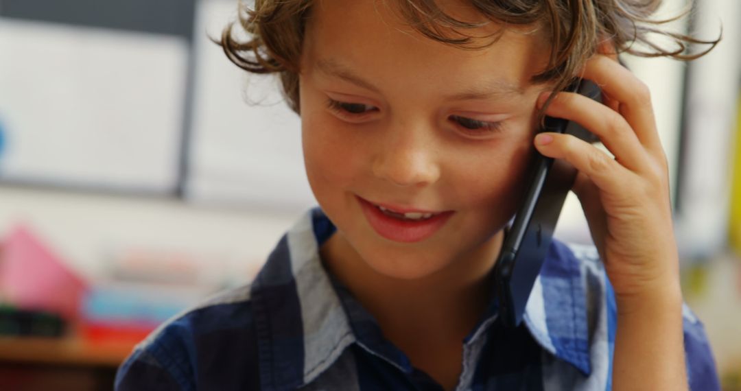 Smiling Schoolboy Talks on Smartphone in Classroom Setting