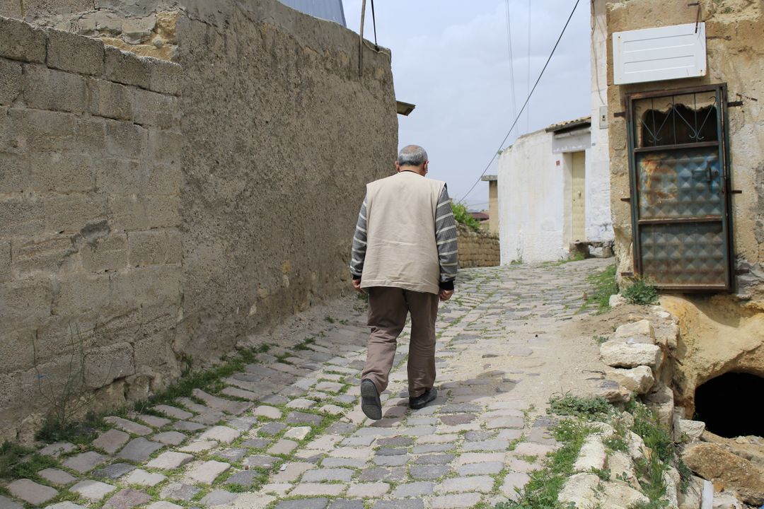 Elderly Man Walking on Cobblestone Street in Historic Village - Free Images, Stock Photos and Pictures on Pikwizard.com