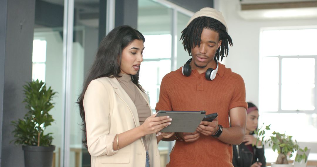 Collaborating on tablet and smartphone in modern open office with diverse professionals