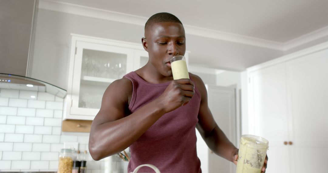 Athletic man drinking green smoothie at home kitchen - Free Images, Stock Photos and Pictures on Pikwizard.com