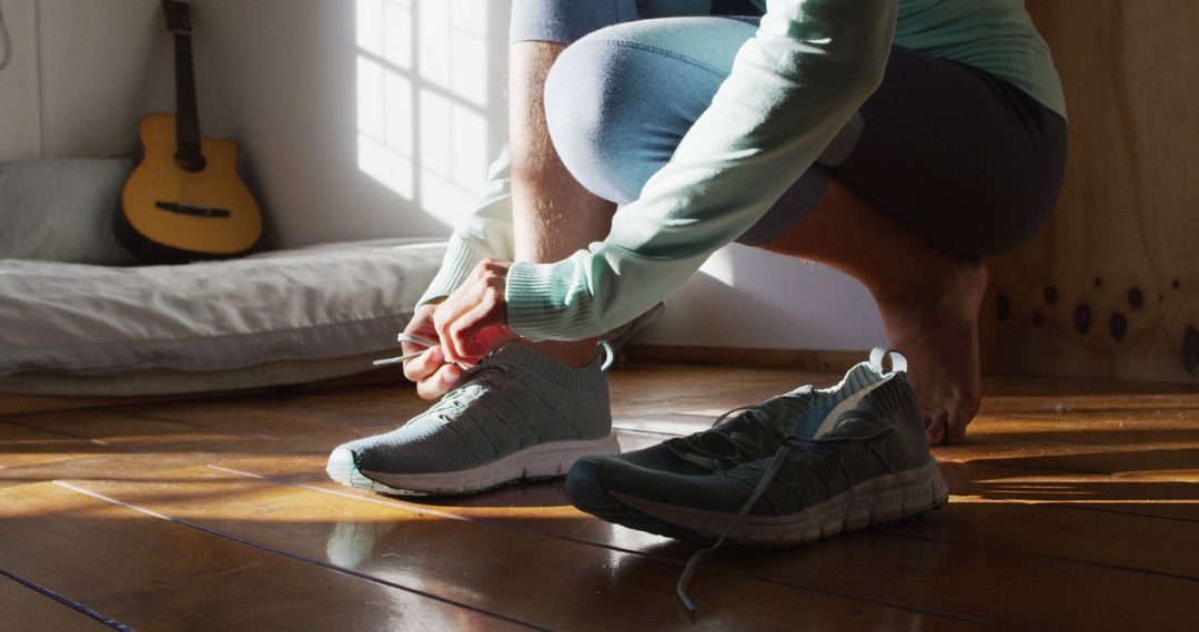 Woman tying running shoes, preparing for exercise at home - Free Images, Stock Photos and Pictures on Pikwizard.com