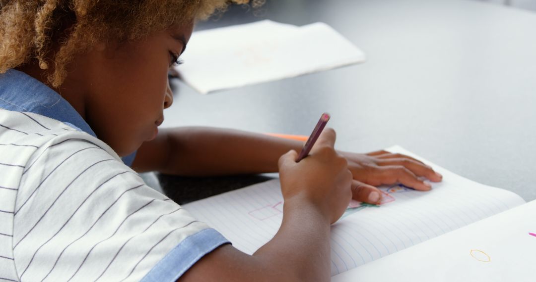 Child Focused on Drawing in Classroom with Colored Pencil